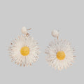 White daisy-shaped earrings on a wooden surface