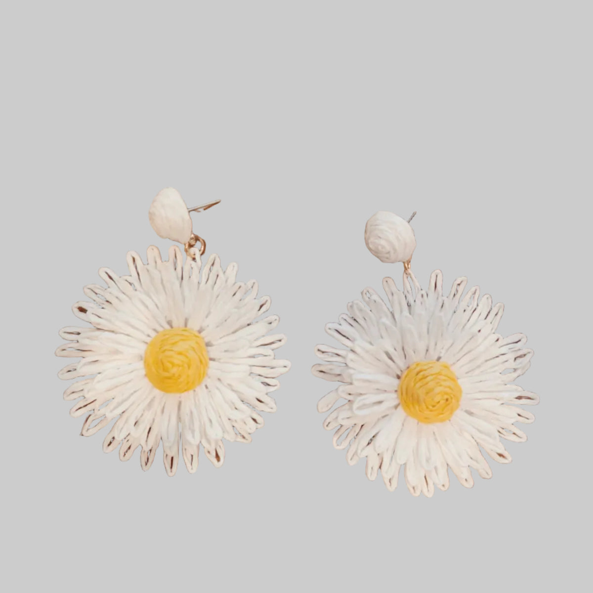 White daisy-shaped earrings on a wooden surface