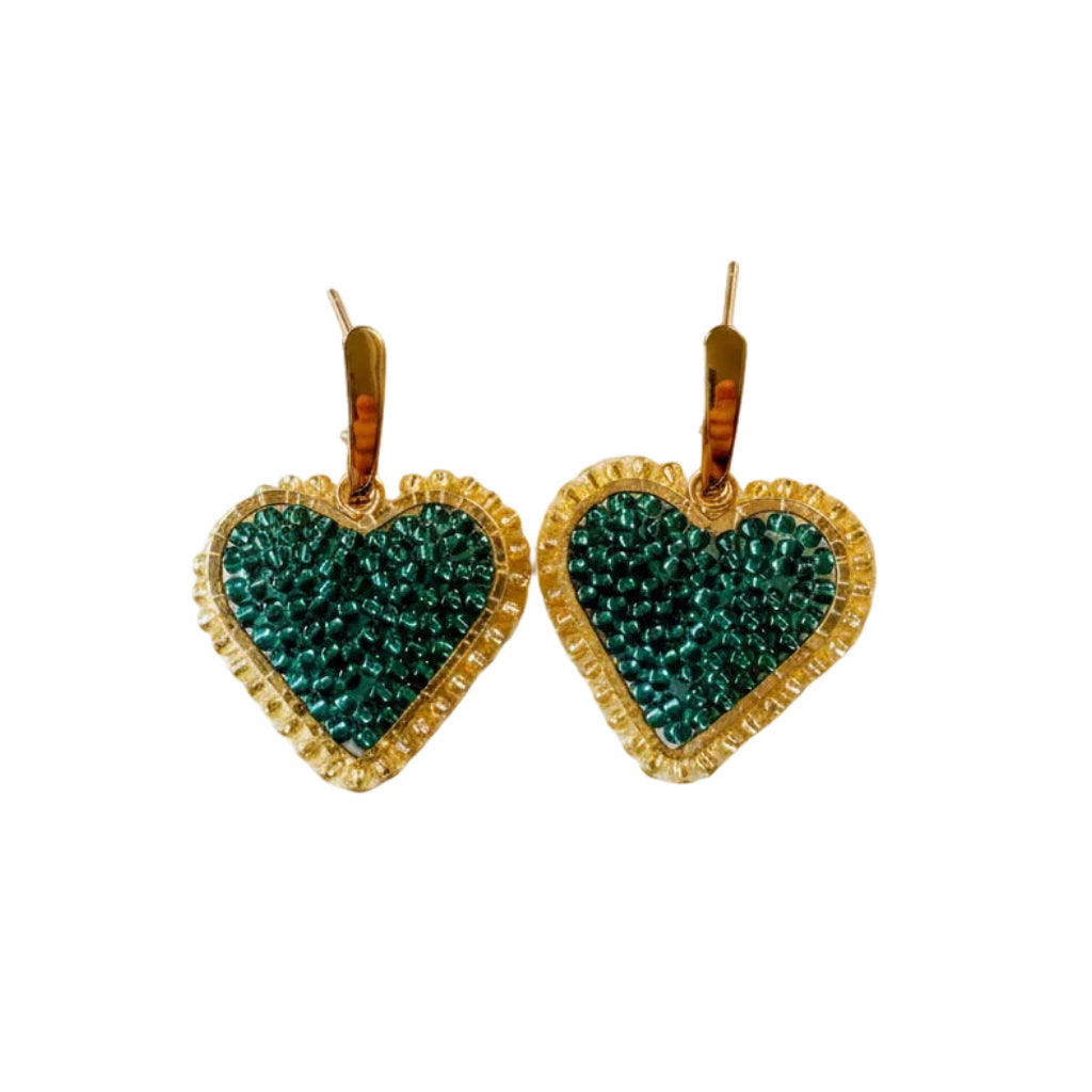 A pair of heart-shaped dangle earrings with textured teal green beadwork and gold beaded borders, hanging from gold fishhook wires on a plain white background.