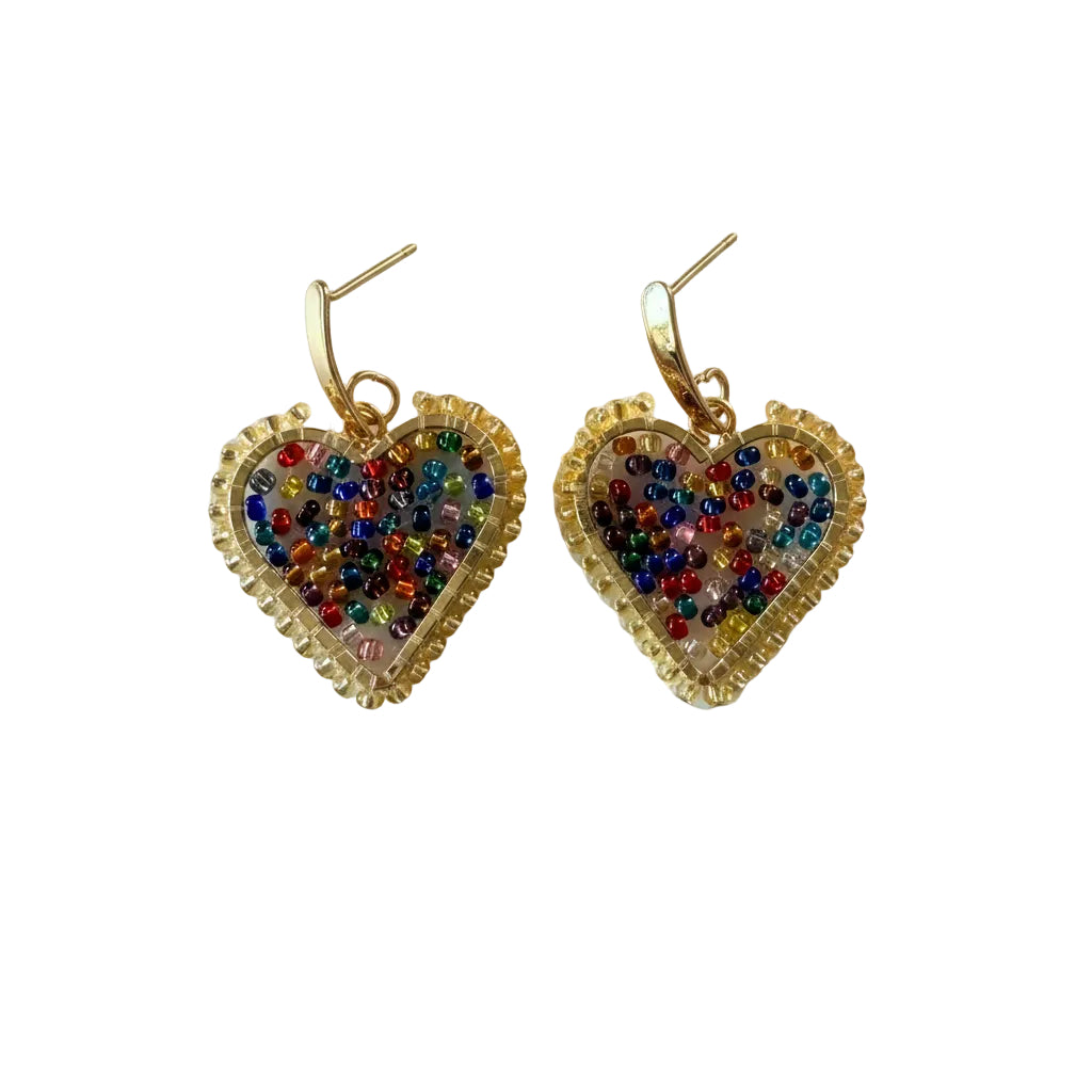 A pair of gold heart-shaped dangle earrings filled with multicolored seed beads, displayed on a light gray background.