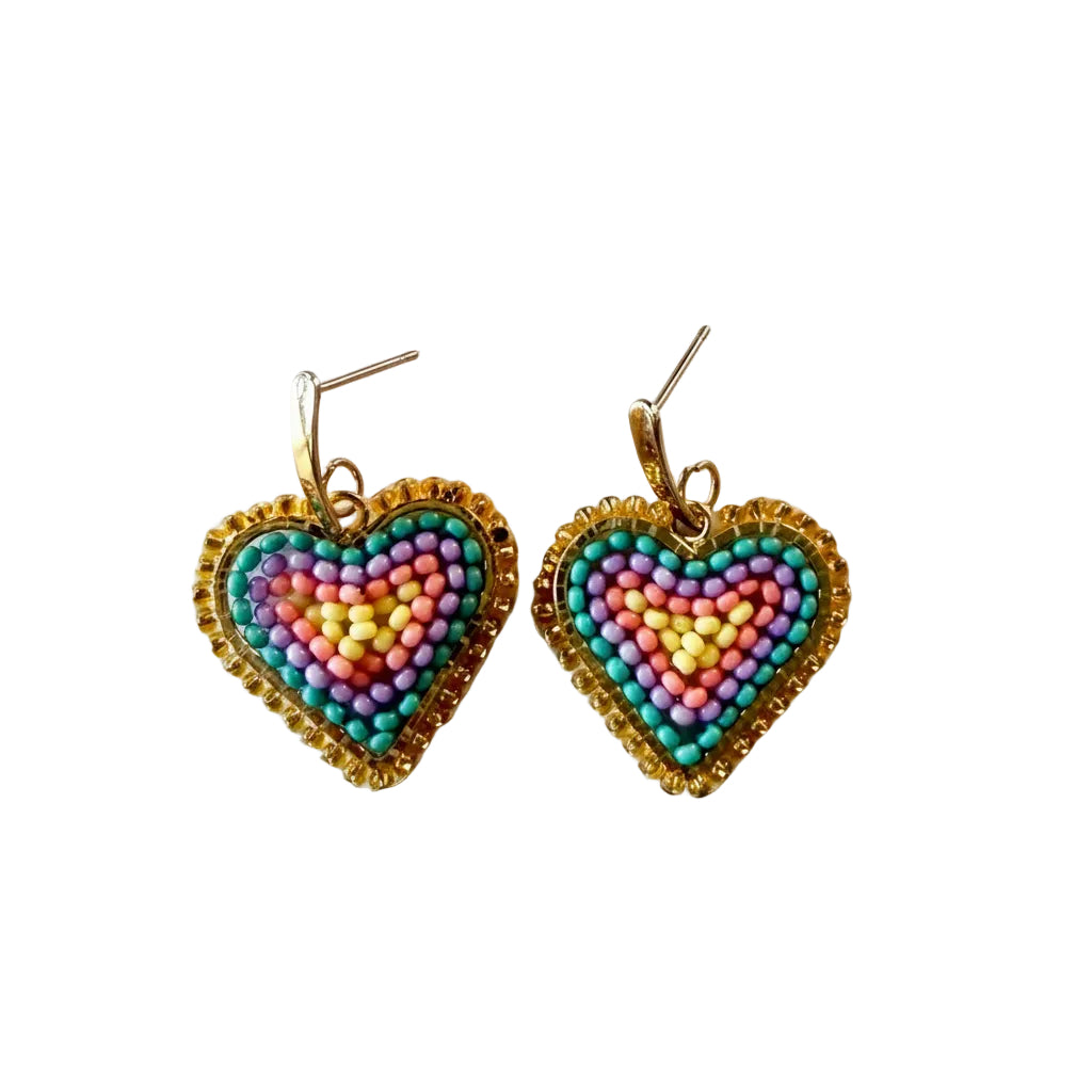 A pair of handmade heart-shaped beaded earrings with gold-toned metal posts, featuring concentric patterns of pink, purple, yellow, and teal beads surrounded by a gold beaded border, displayed on a light gray background.