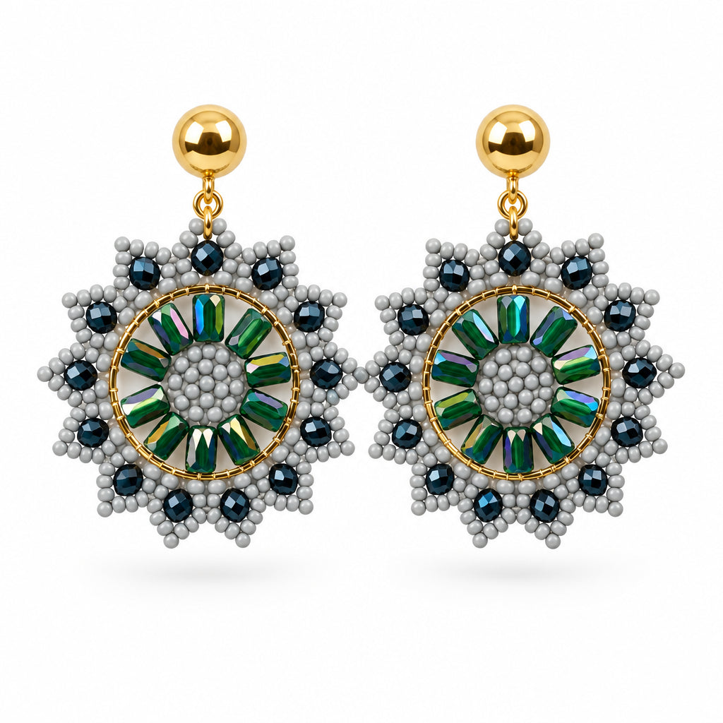 A pair of gold-tone dangle earrings with intricate green and blue beaded circular sunburst designs, displayed on a white backing card against a white background.