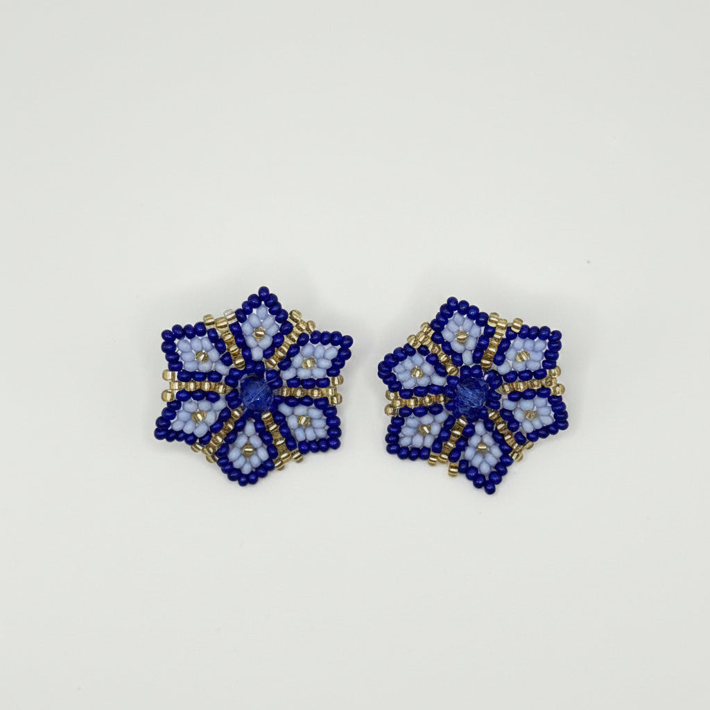A pair of handmade beaded flower-shaped earrings in royal blue, light blue, and gold, displayed on a clean white background.
