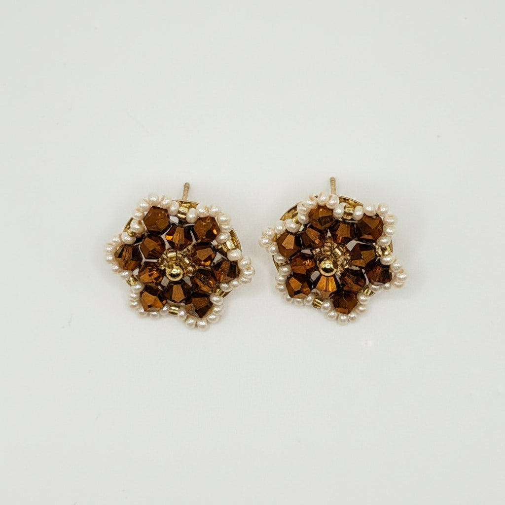 A pair of small gold-toned stud earrings with clustered brown and clear rhinestones, photographed on a plain light gray background.