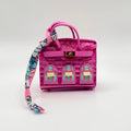 A small pink textured handbag with a matching pink top handle and a long patterned scarf draped from the side, photographed on a clean white studio background.