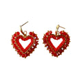 A pair of handmade heart-shaped dangle earrings made from red seed beads, clear faceted rhinestones, and gold-tone metal findings, displayed on a plain light background.