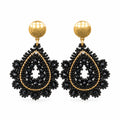A pair of black beaded teardrop dangle earrings with gold-toned studs, displayed on a clear plastic card against a white background.