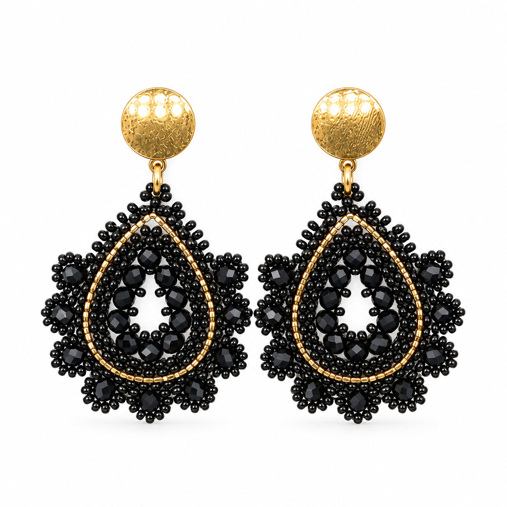 A pair of black beaded teardrop dangle earrings with gold-toned studs, displayed on a clear plastic card against a white background.