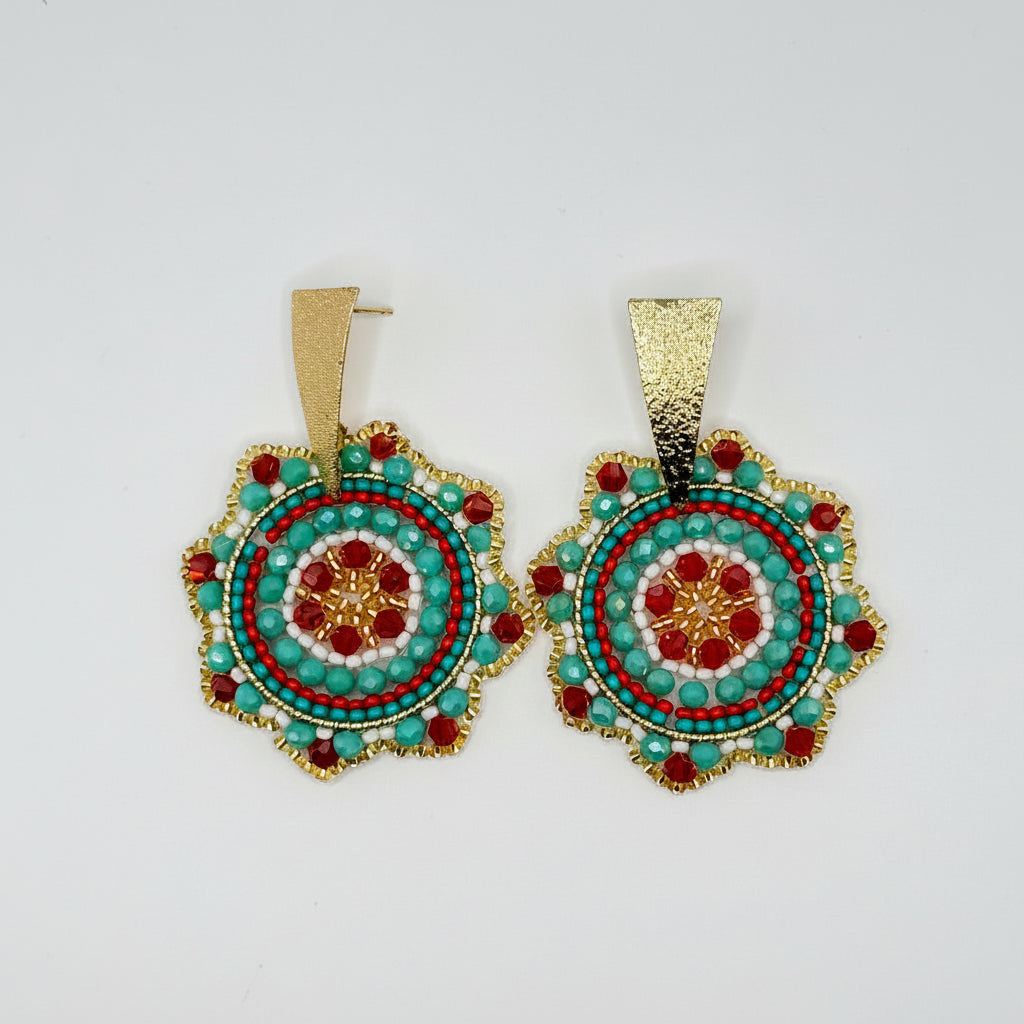 A pair of handmade beaded earrings with gold-tone metal frames and posts, featuring intricate circular beadwork in turquoise, red, white, and gold.