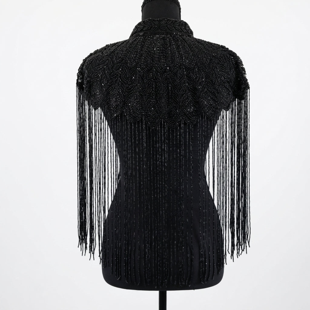 A black beaded and fringed shawl or cape draped over a black mannequin torso, shown against a plain white background.