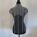 A silver beaded shawl with intricate geometric patterns and long hanging fringe, displayed on a black mannequin torso against a light neutral background.