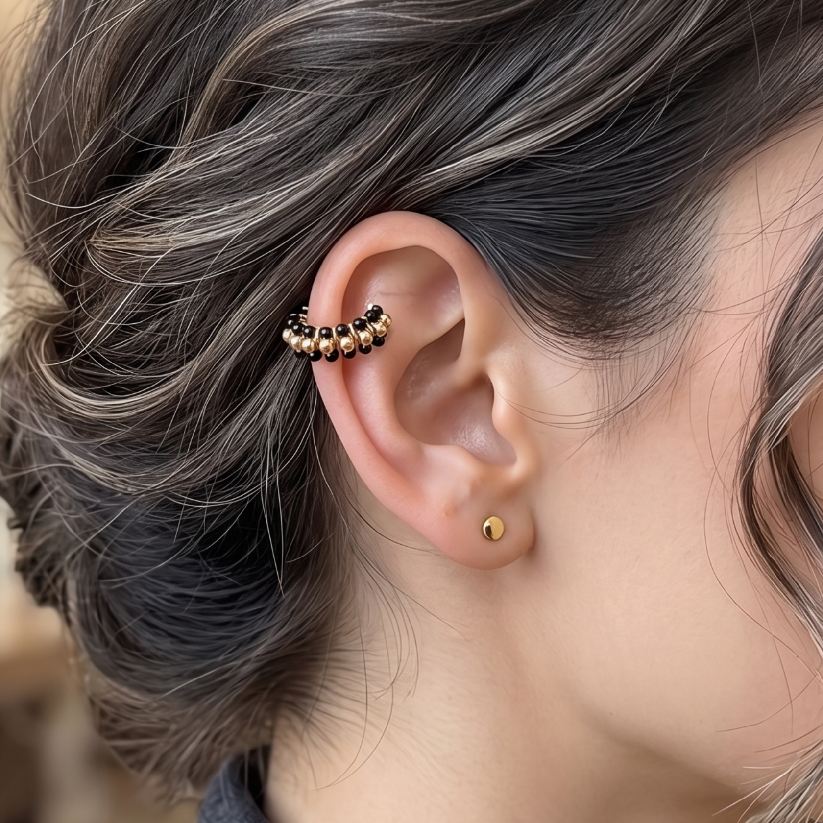 Close-up of a woman's ear wearing a small earring with a blurred indoor background