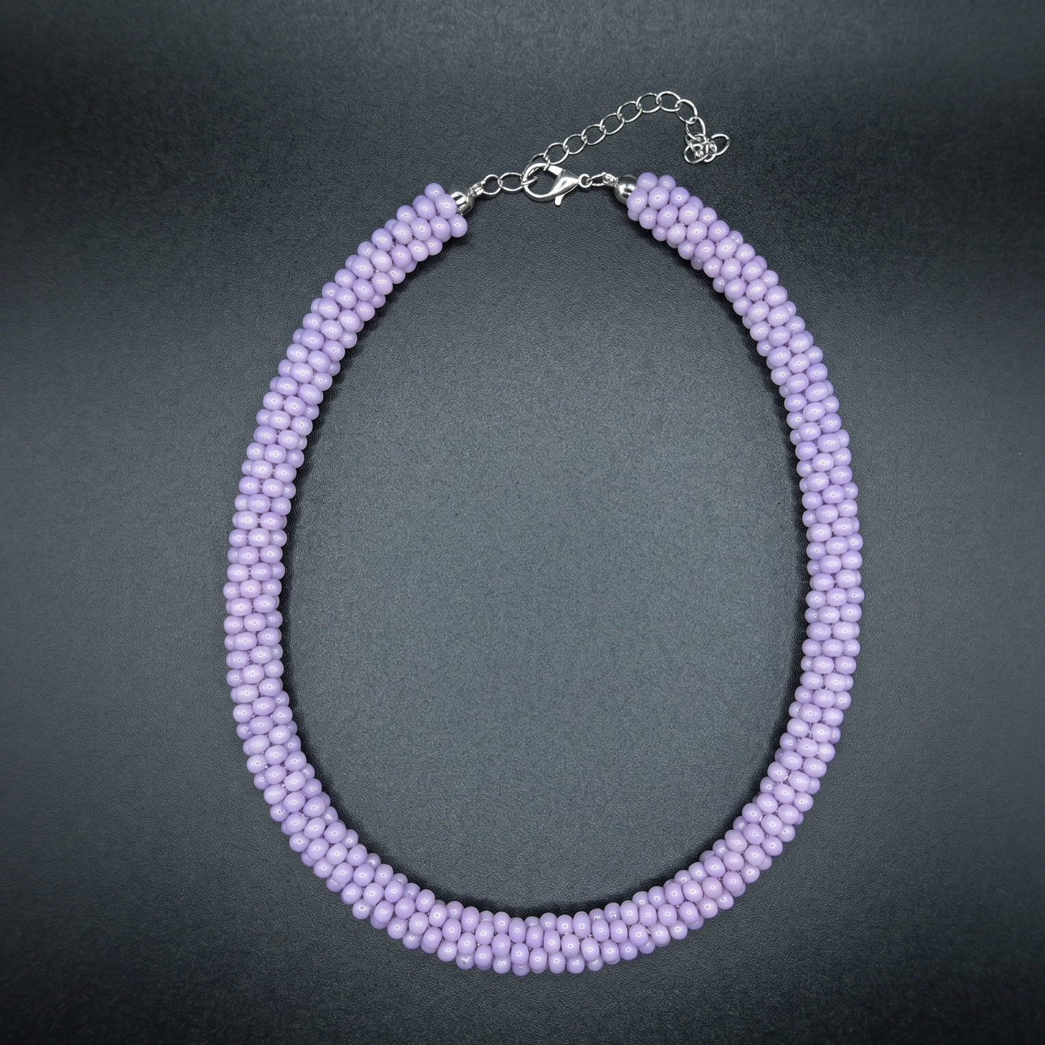 Purple beaded necklace on a dark surface