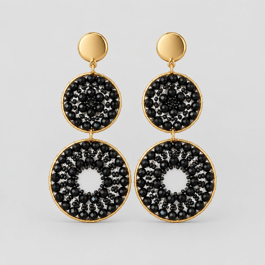 A pair of black and white patterned dangle earrings with gold-tone studs, displayed on a white backing card labeled 'STAINLESS STEEL'.