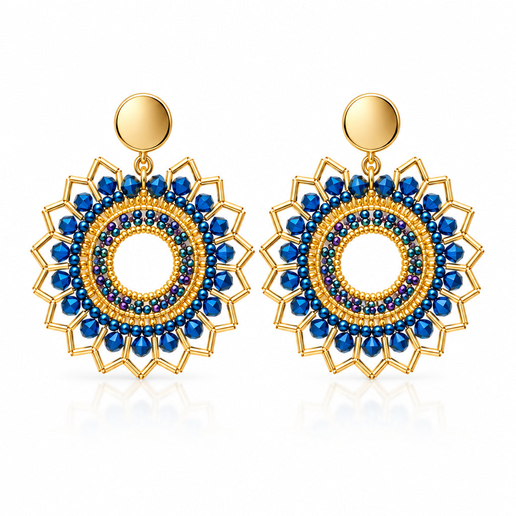 A pair of gold-toned statement earrings with blue rhinestone accents, displayed on a small white card against a white background.