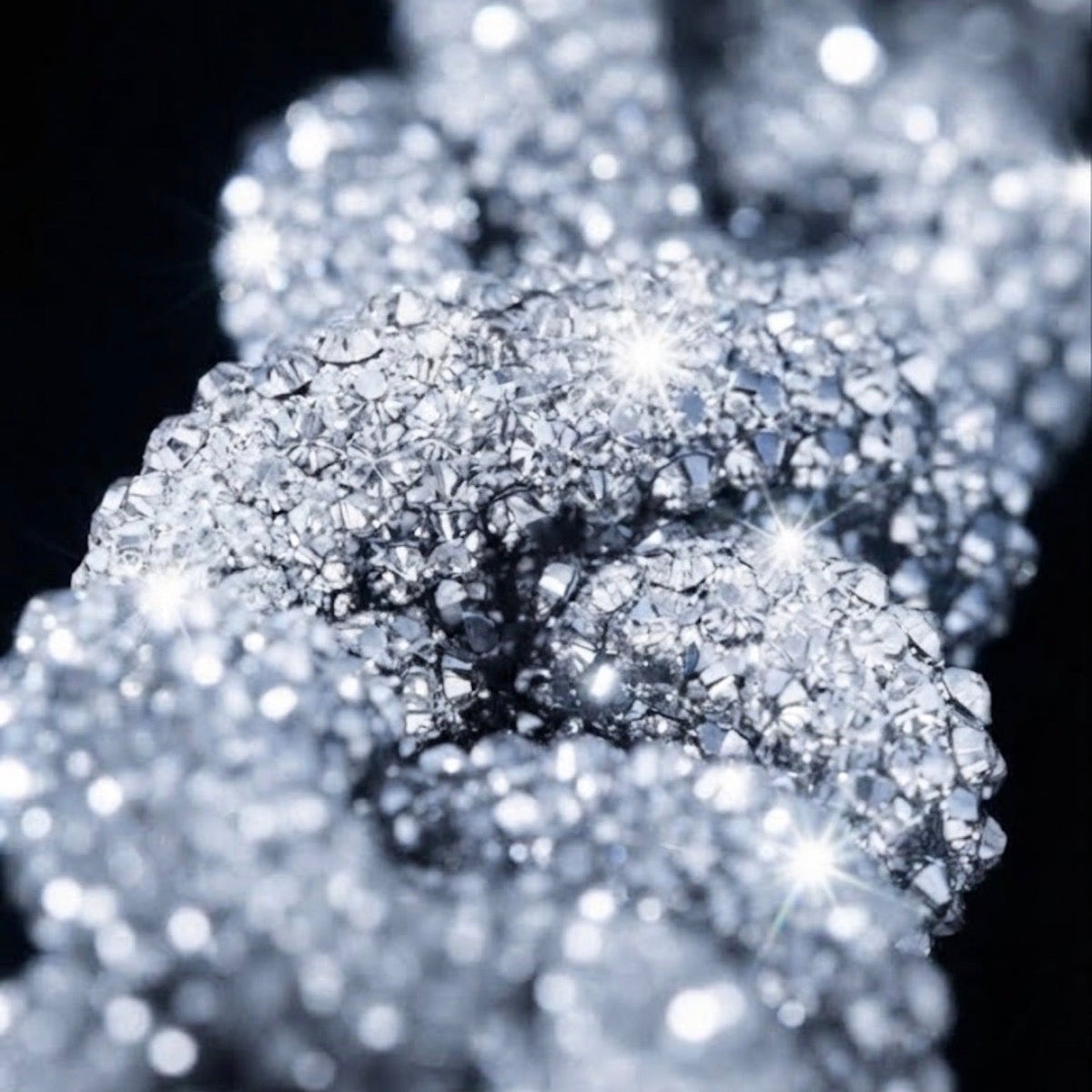 A close-up macro shot of sparkling clear gemstone-like crystals on a black background, with bright starburst highlights and a soft bokeh effect.